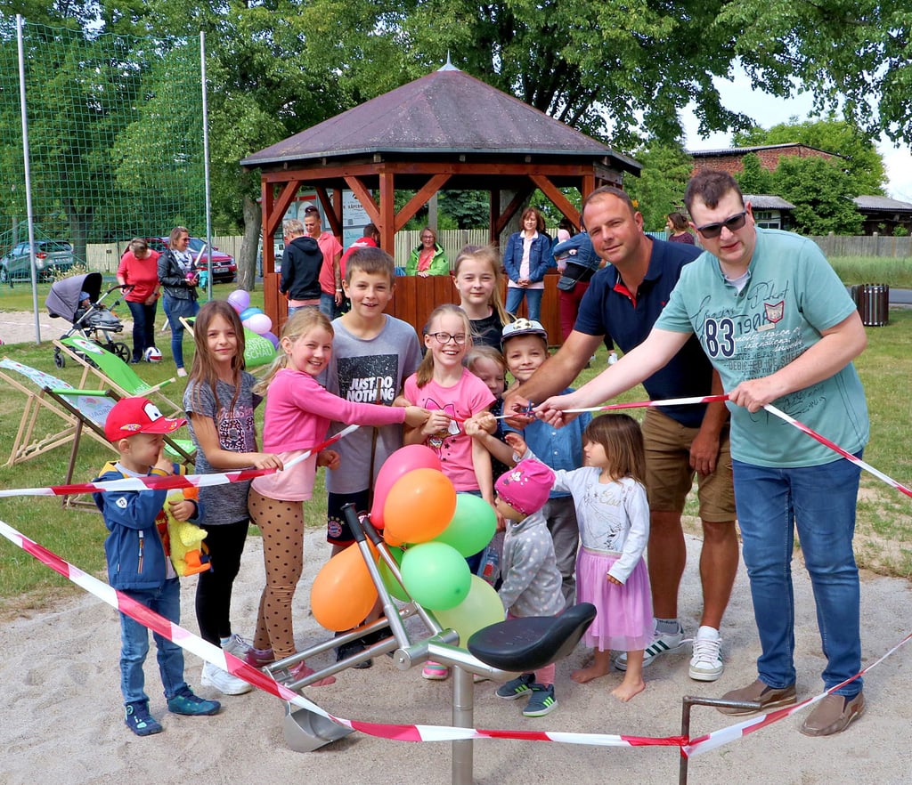 Ortsbürgermeister Andreas Nowack gibt am Mittwochnachmittag, assistiert von etlichen Kindern, den Weg frei zu dem neuen Sandbagger auf dem Spielplatz.