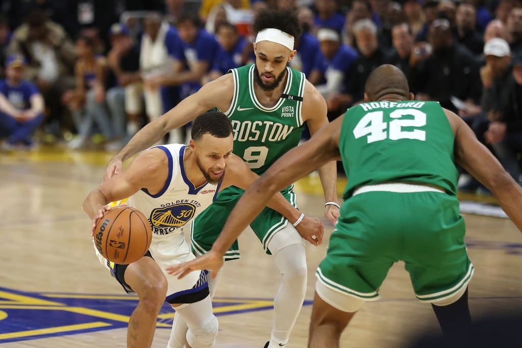 Stephen Curry (l, 30) von den Golden State Warriors in Aktion mit Bostons Al Horford (M, 42) und Derrick White (9).