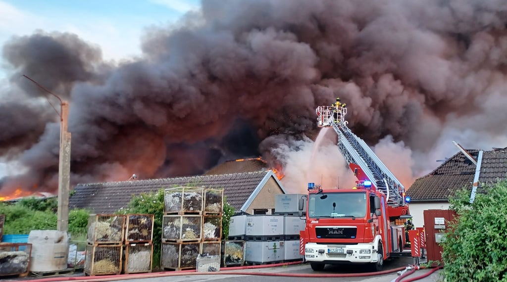 Feuerwehrleute löschen von einer Drehleiter aus einen Brand in einem Unternehmen, das Kunstsoffe verarbeitet.
