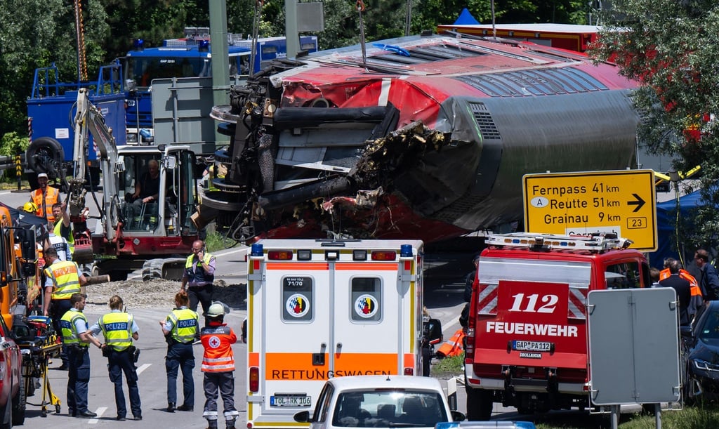 Die Rettungskräfte heben nach dem schweren Zugunglück einen der Waggons an.