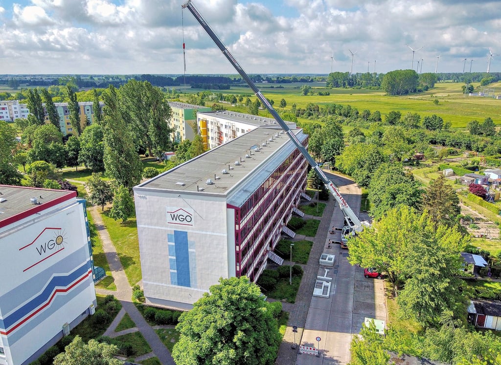 Mit einem Kran, der auf der Karl-Marx-Straße stand, wurden schwere Bauteile über den Plattenbau gehoben.