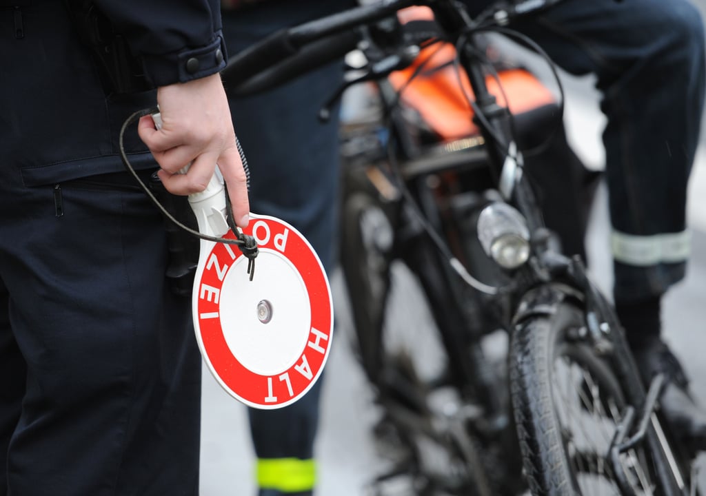 Ein Polizeibeamter mit Halte-Kelle stoppt einen Radfahrer
