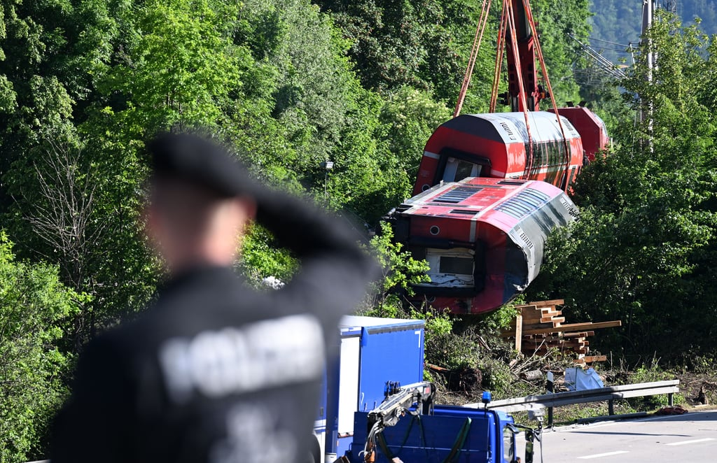 Ein Polizist betrachtet aus der Ferne den Unfallort, wo zwei Waggons noch geborgen werden müssen. Nach dem Zugunglück von Garmisch-Partenkirchen gehen die Aufräumarbeiten voran.