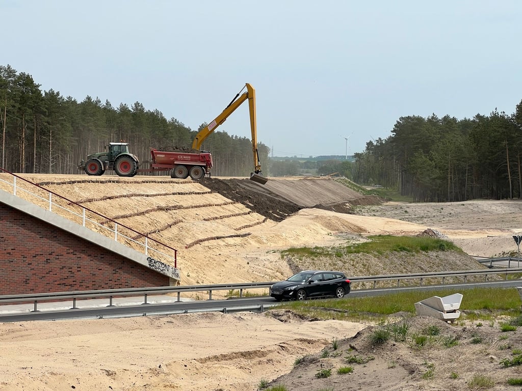 Der laufende Verkehr rollt bereits unter der künftigen Autobahntrasse durch. An der Böschung sind Faschinen zu erkennen, die dem Bauwerk Stabilität verleihen sollen.