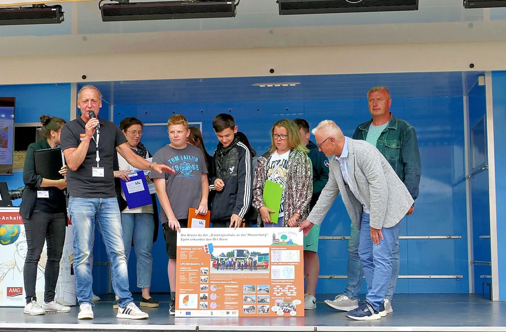Die Klasse 6a der Schule an der Wasserburg Egeln zeigt stolz ihre Ergebnisse an Bernd Nimmich und Klaus Saplata.