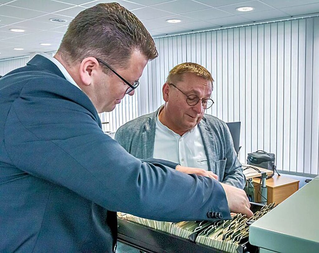 Landrat Christian Tylsch und Abteilungsleiter Klaus Hofmann blättern in alten Karteikarten.
