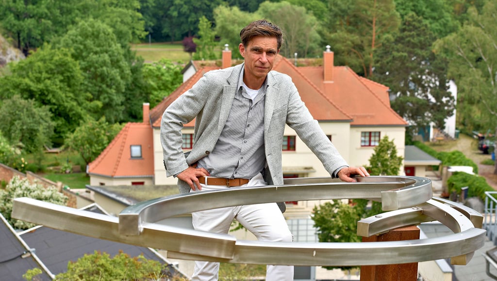 Matthias Rataiczyk, Leiter der Kunsthalle Talstrasse, steht im Felsengarten hoch über der Saale vor der Arbeit „Schwing“ von Thomas Leu.