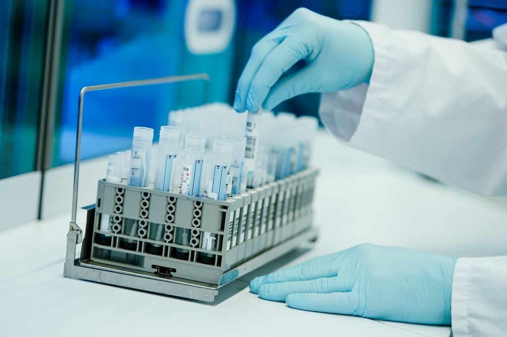Ein Mitarbeiter hält in einem Labor PCR-Teströhrchen in den Händen.