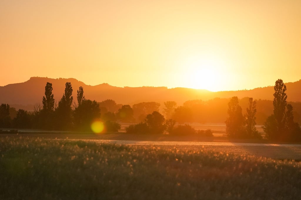 Die aufgehende Sonne lässt die umliegende Landschaft in einem orangefarbenen Licht aufleuchten. Auf der gesamten Nordhalbkugel ist es am 21. Juni am längsten hell.