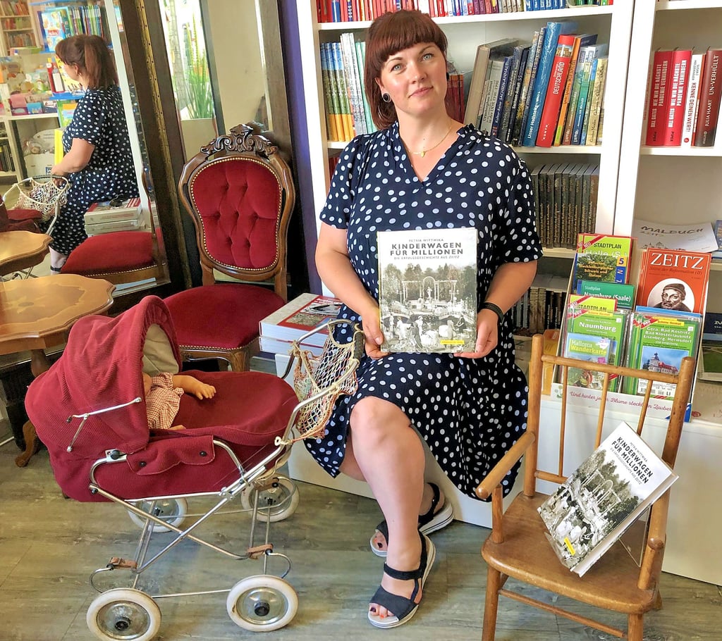 Buchhändlerin Sabine Mehland freut sich, dass sie das neue Buch „Kinderwagen für Millionen“ jetzt den Kunden in der Gutenberg-Buchhandlung anbieten kann. Zum Fototermin rückte sie natürlich auch den Naether-Kinderstuhl, ein Geschenk von Ernst-Albert Naether, und ihren Zekiwa-Puppenwagen zurecht.