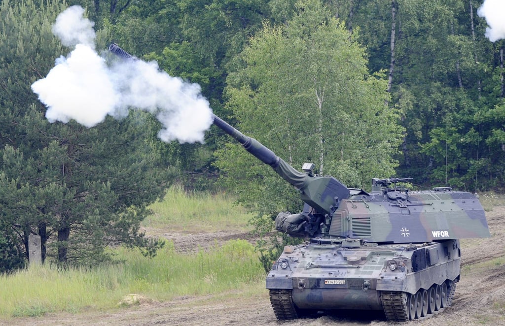 Eine Panzerhaubitze 2000 der Bundeswehr feuert bei einer Fahrt auf dem Truppenübungsplatz.