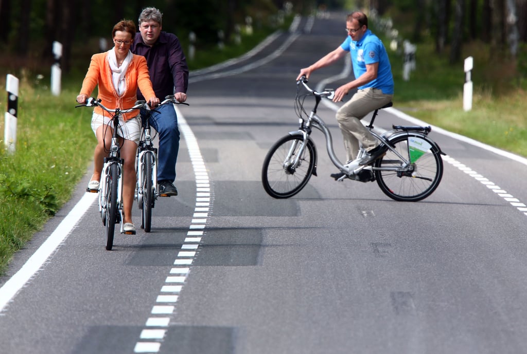 Radfahrer sind auf einem Fahrradstreifen auf einer Landstraße unterwegs.