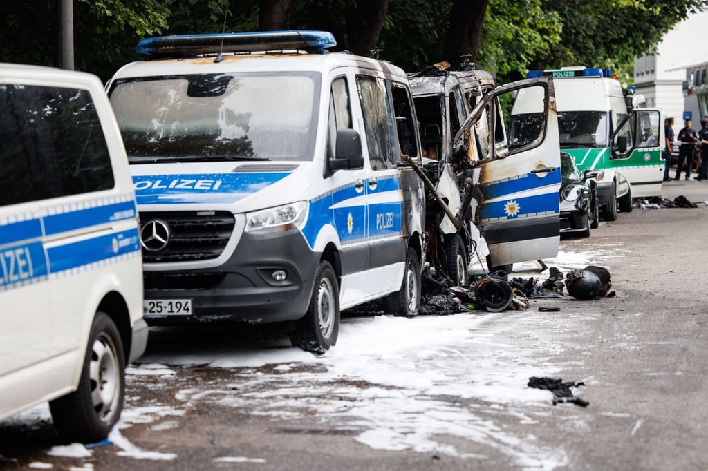 Polizeiautos die in der Nacht gebrannt hatten, stehen am frühen Morgen zwischen anderen geparkten Einsatzfahrzeugen der Polizei.