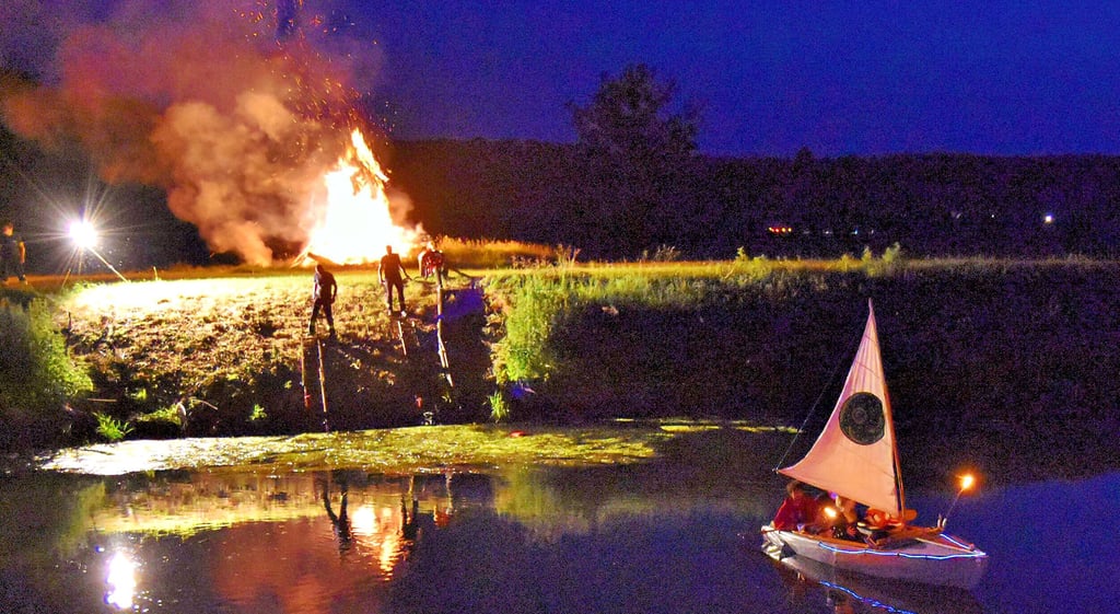 „Unstrut in Flammen“: Das „Flaggschiff“ Himmelsscheibe kreuzt vor dem von einem Feuer erhellten Ufer der Unstrut.