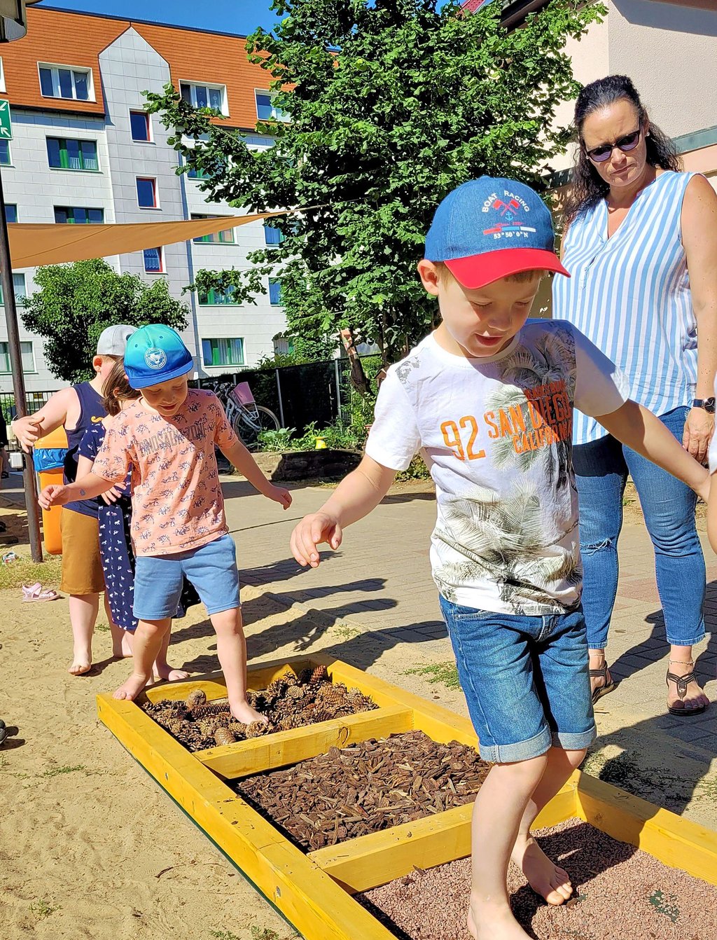 Die Kinder erfühlen mit ihren Füßen verschiedene Untergründe auf dem Naturpfad.