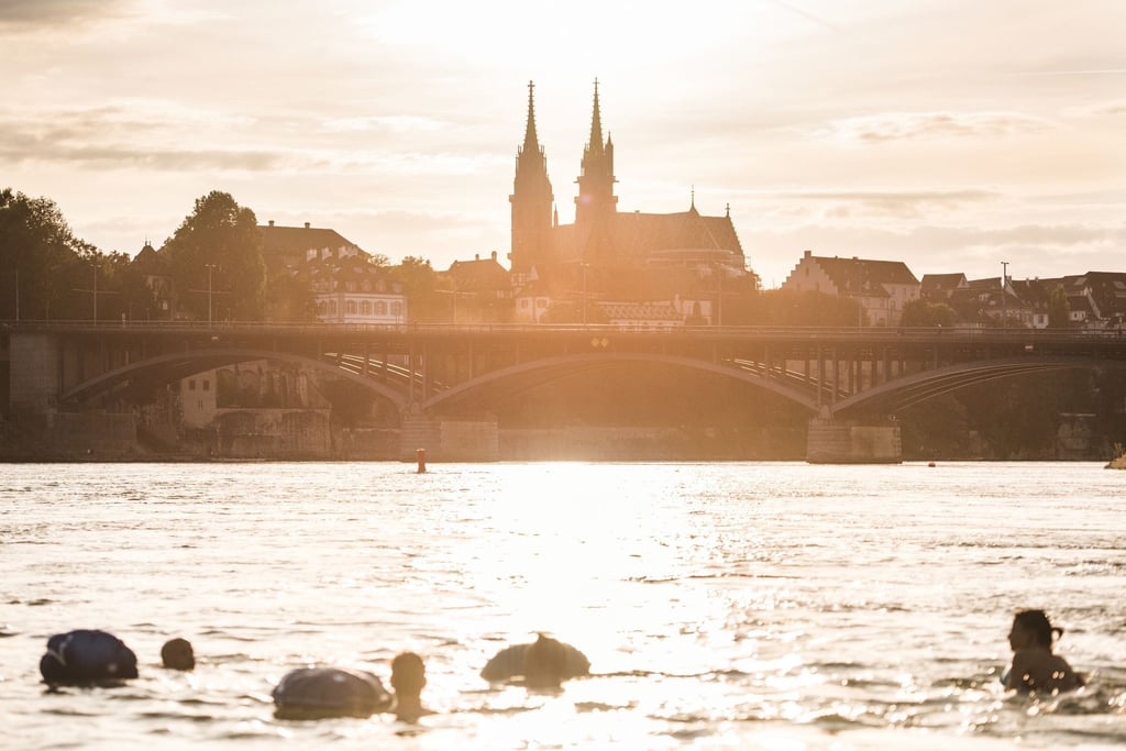 Panoramablick aufs Münster: Menschen treiben mit ihrem Wickelfisch in Basel den Rhein hinab.