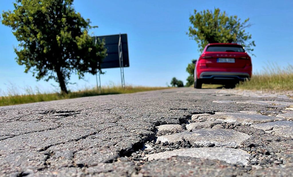 Alte Pflasterteine brechen unter dem brüchigen Asphalt durch. Die Kreisstraße K1243 Richtung Grube Alfred ist in desolatem Zustand.
