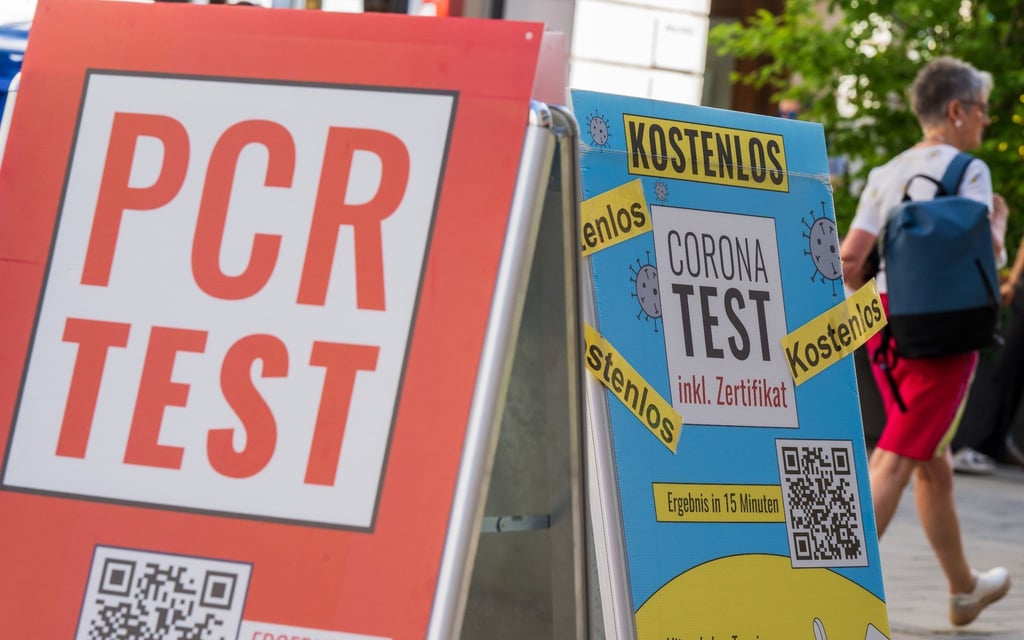 Schilder bewerben vor dem Eingang einer Apotheke in der Münchener Innenstadt Corona-Tests.