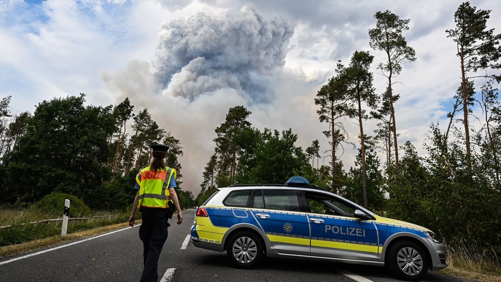 Ein Polizeiauto sperrt die Straße im Waldbrandgebiet in der sächsischen Gohrischheide ab.