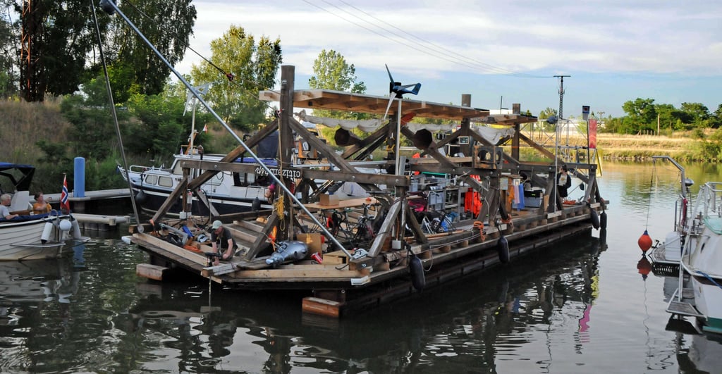 Nur durch die Kraft der Gemeinschaft bewegt sich das umgedrehte Dach auf dem Wasser. Der Sportboothafen in Calvörde ist eine Zwischenstation auf der künstlerischen Forschungsreise. Mit dem Holzdach des Zentrums für Kunst und Urbanistik geht es von Berlin zur documenta fifteen nach Kassel.