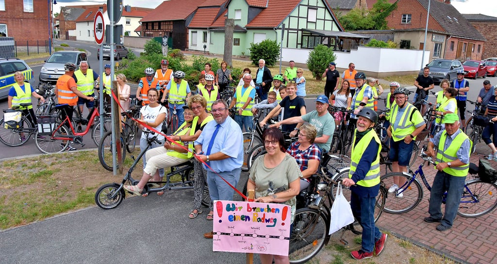 Sandra Hietel-Heuer (v.l.), Mitglied des Landtages, BI-Sprecherin Brigitte Dobbelmann und Einheitsgemeinde-Bürgermeister Hans-Werner Kraul zerschneiden das symbolische Band zur Freigabe des ersten Teilabschnitts vom straßenbegleitenden Radweg der Landesstraße 24. Mitglieder der BI und Freunde radeln auf dem neuen Weg von Rätzlingen nach Kathendorf und weiter bis nach Wegenstedt.