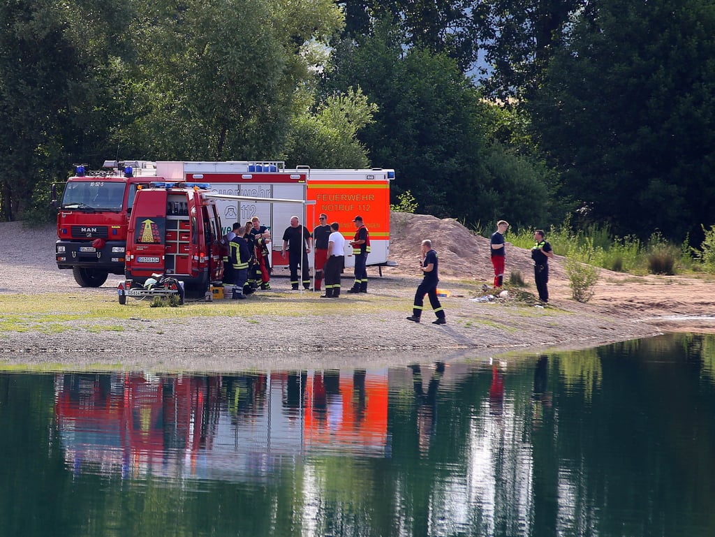 Fahrzeuge der Feuerwehr stehen an einem Baggersee. Ein 25-Jähriger ist in einem Badesee im Landkreis Göttingen ertrunken. Nach einer groß angelegten Suchaktion bargen Rettungstaucher die Leiche am aus dem Rosdorfer Kiesteich.