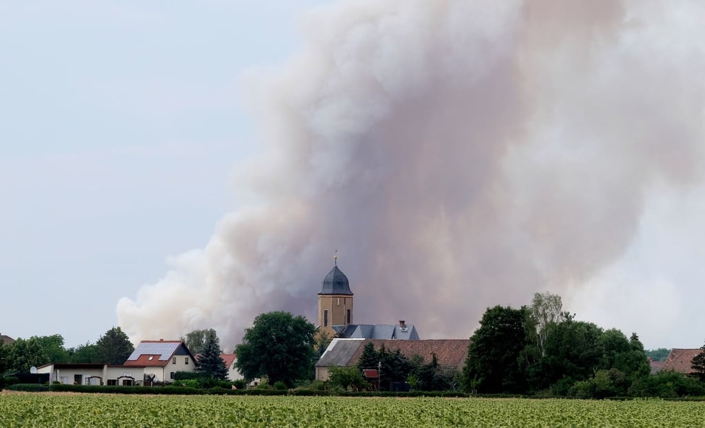 Rauch eines Waldbrandes steigt über dem Dorf Lichtensee (Landkreis Meißen) auf. Seit Donnerstag brennt es in der Gohrischheide.