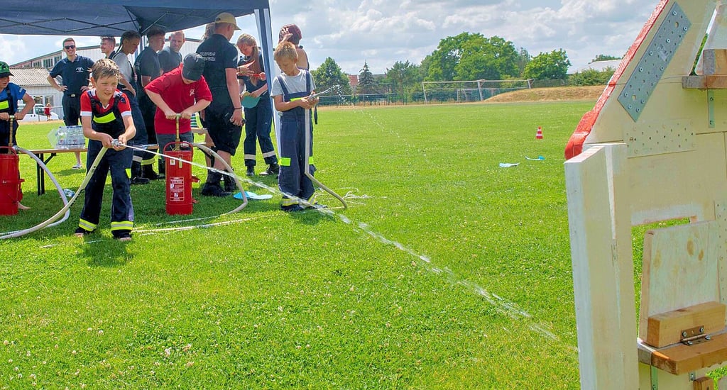 Am Spritzenhaus kommt es auf Genauigkeit an. Trifft der Wasserstrahl die Holzklappe mit den Flammen, ist der Brand gelöscht.