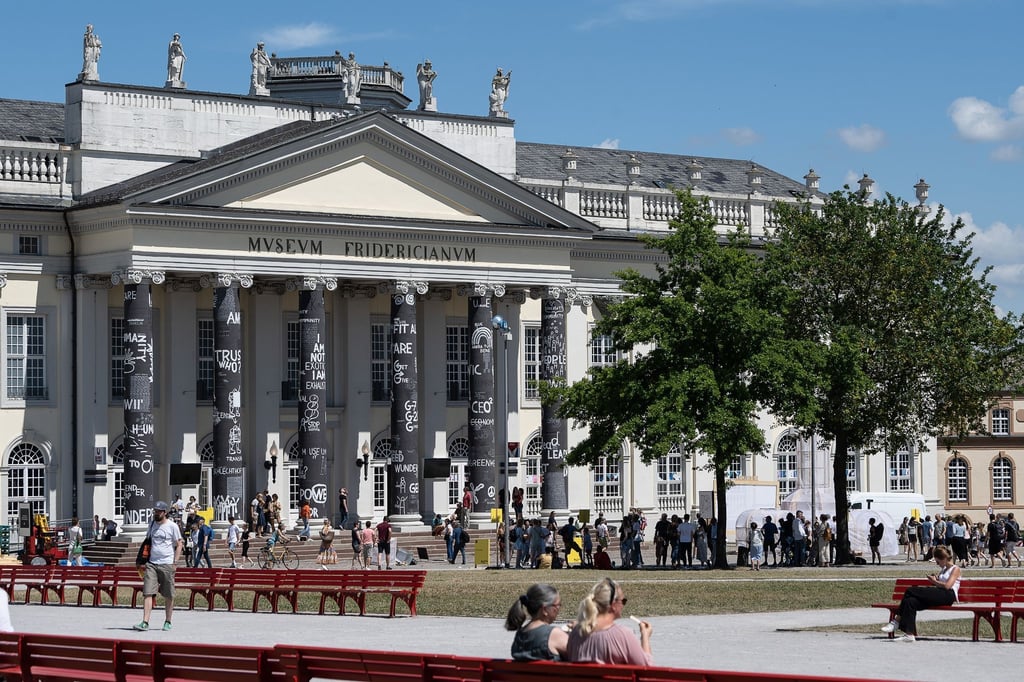 Besucher stehen vor dem Museum Fridericianum auf der documenta fifteen.