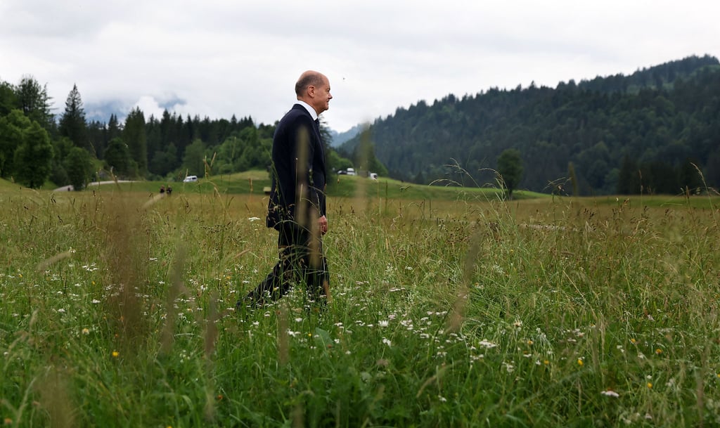 Olaf Scholz stapft missmutig durch das hohe Gras von Elmau von dannen.