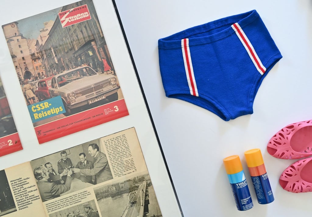Eine Badehose vom VEB Strickwaren Oberlungwitz aus den 1970er Jahren, Badeschuhe „Carola“ und Sonnenschutzspray „Violetta“ sind in der Ausstellung „Grenzen der Freundschaft. Tourismus zwischen DDR, CSSR und Polen“ im Dokumentationszentrum Alltagskultur der DDR zu sehen.