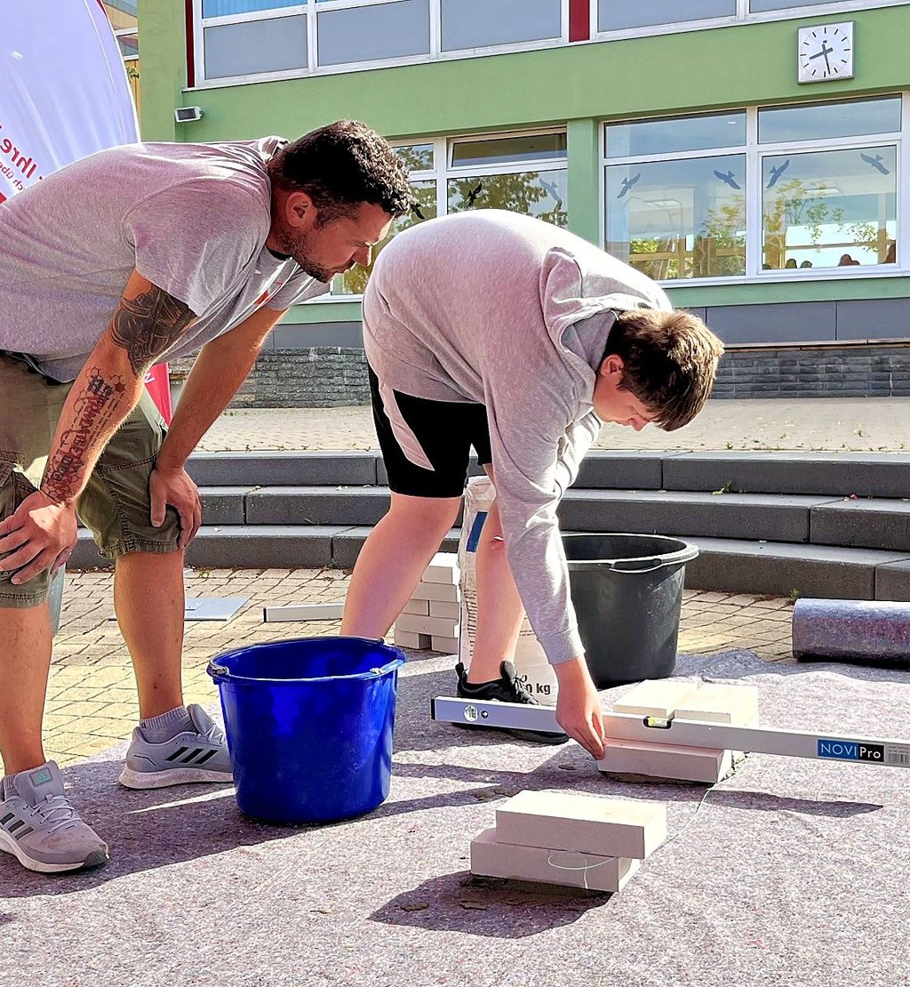 Hochbaumeister Christoph Behnke (links) erklärt Justin Tschitschilewsky, wie ein Stein mit der Wasserwaage ausgerichtet wird.