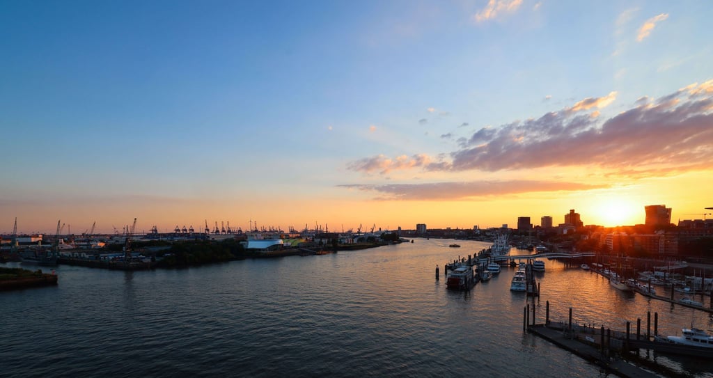 Die Sonne geht über der Elbe und dem Hamburger Hafen unter.