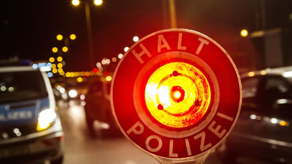Mit einer Haltekelle stoppt ein Polizist Fahrzeuge auf der Autobahn