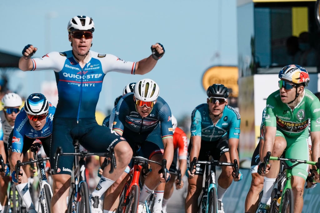 Der Niederländer Fabio Jakobsen (l) überquert die Ziellinie vor dem Belgier Wout Van Aert (r) und dem Dänen Mads Pedersen.