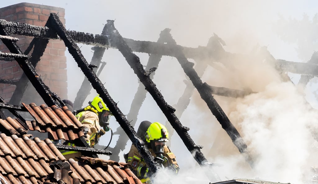Feuerwehrmänner arbeiten nach einem Band in einem qualmendem Dachstuhl