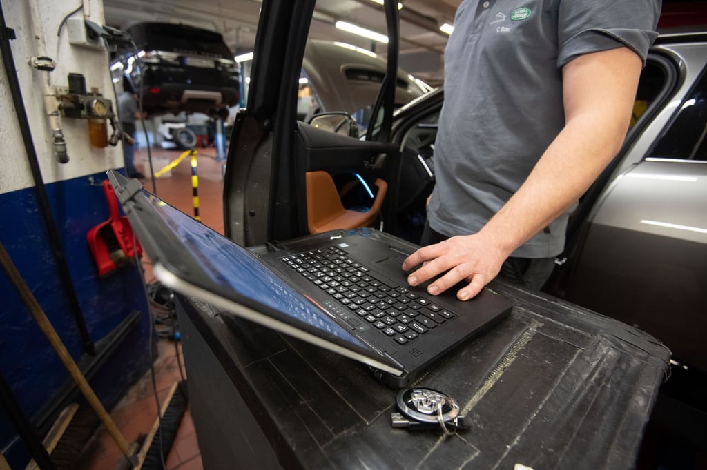 Ein KFZ-Mechaniker wartet in einer KFZ-Werkstatt einen elektrisch angetriebenen Jaguar I-Pace Vorführwagen.