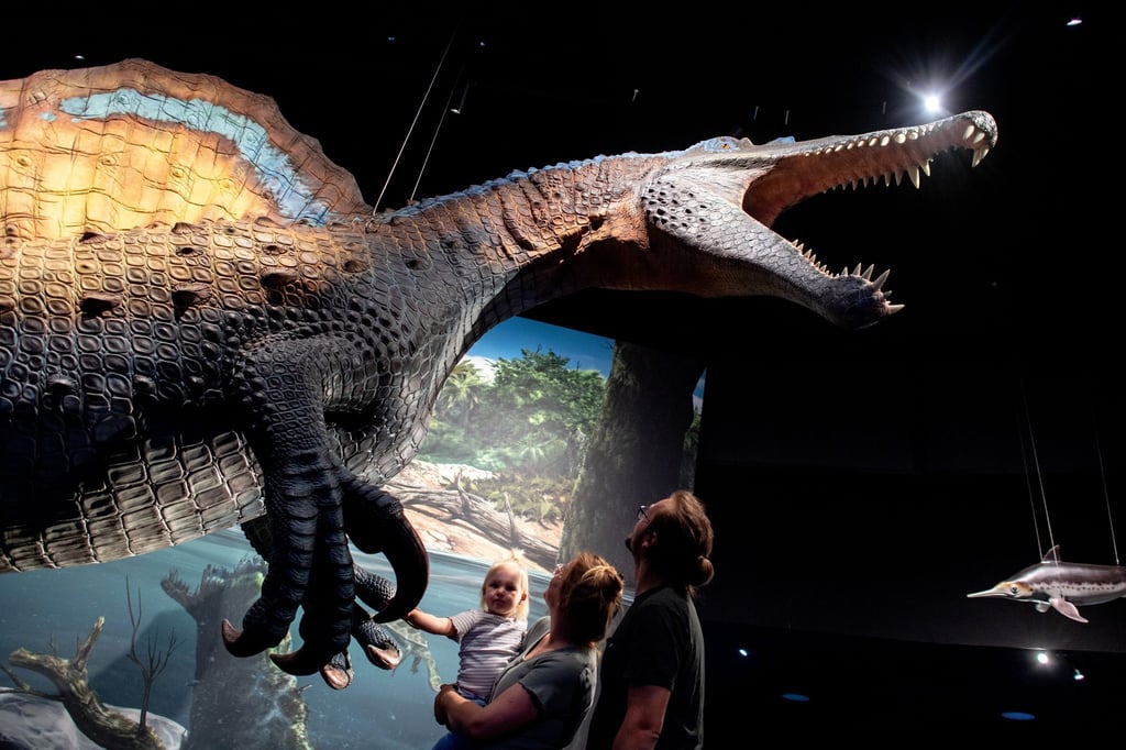 Eine Familie betrachtet ein lebensgroßes Modell eines Spinosaurus in der neuen Erlebnisausstellung „Saurier - Giganten der Meere“.