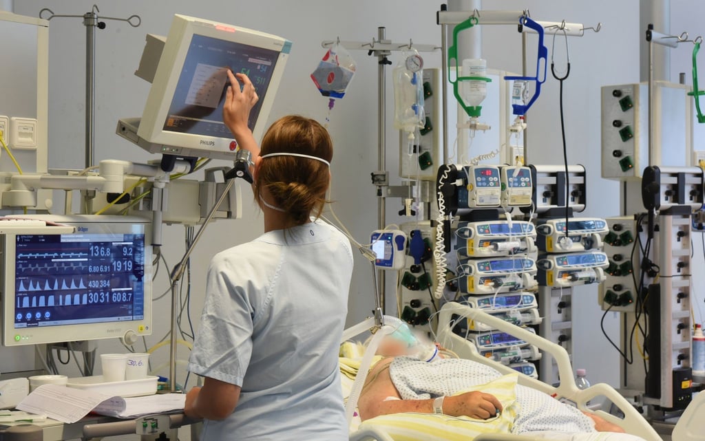 Auf einer Station im Klinikum St. Georg steht eine Mitarbeiterin am Bett einer Patientin.