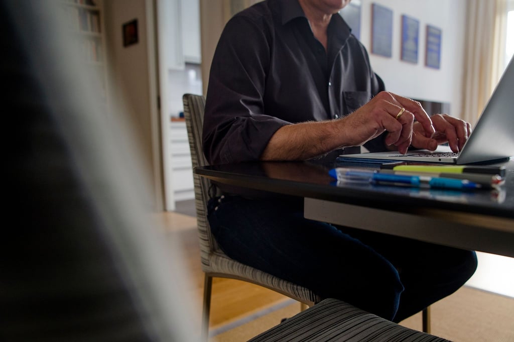 Ein Mann sitzt Zuhause am Esstisch und arbeitet.