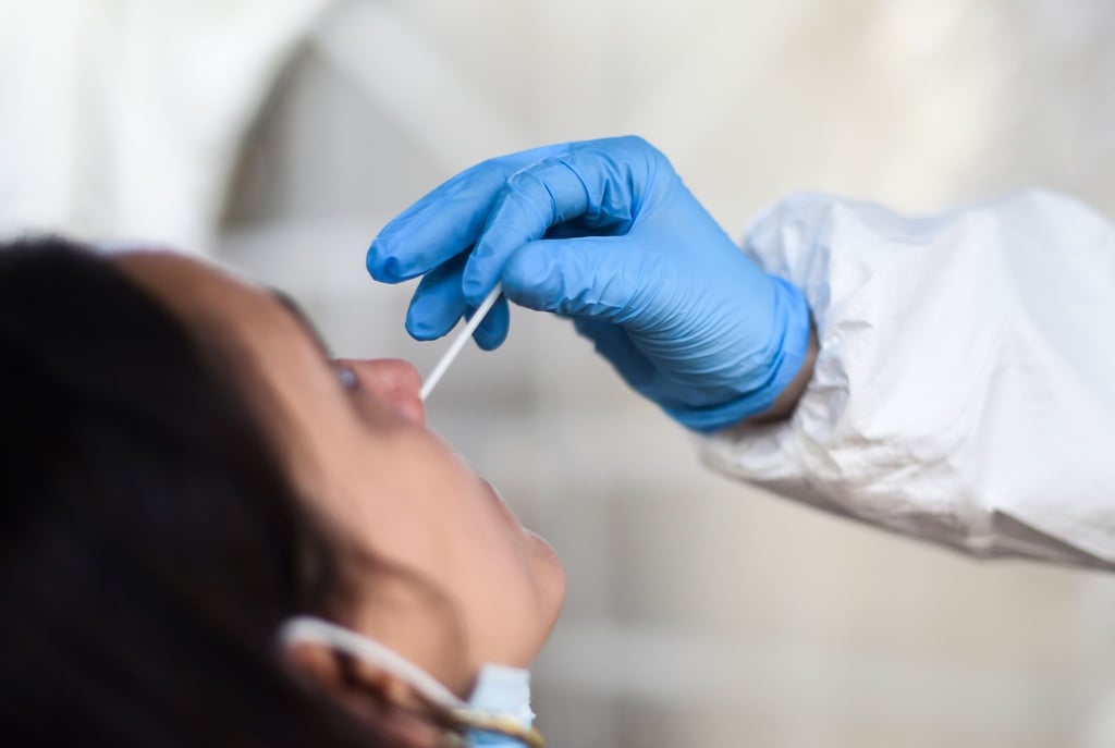 Eine Mitarbeiterin eines Testzentrums entnimmt einer Frau einen Nasenabstrich für einen Corona-Test.