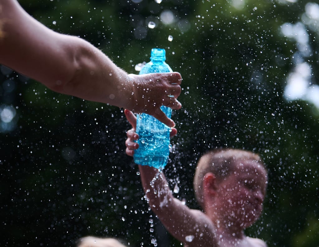 Eine Mutter füllt für ihren Sohn Wasser vom Springbrunnen ab.