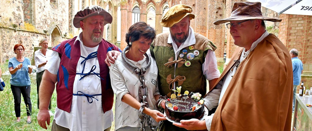 Die Männer, die Viola Tiepelmann bei ihren legendären Nachtstadtführungen begleitet haben: Uwe Stück als Scharfrichter, Tom Hebäcker als Gastronom sowie Roland und Daniel Hinze als Fackelmeister (v.r.) verabschieden die Chefin der Zerbster Tourist-Information mit einer Torte. Sie selbst schlüpfte in die Rolle der Butterjungfer, der Magdalena von Servesta.