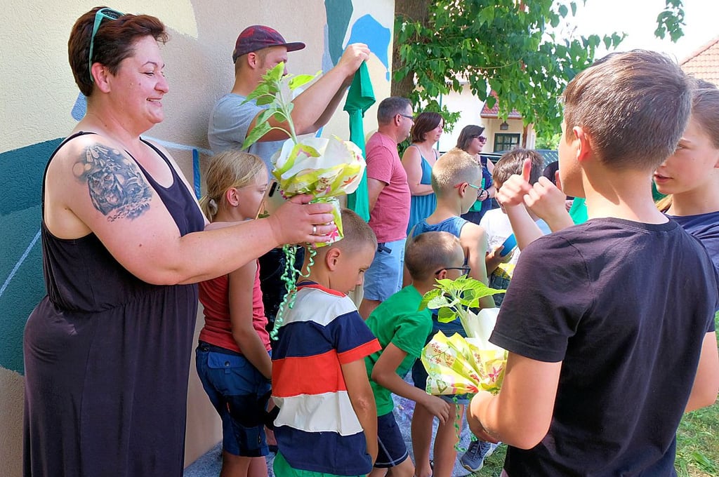 Martina Flade (links) vom Projektsponsor enviaM bekommt von den Kindern als Dankeschön einen Topf mit einer Sonnenblume überreicht.