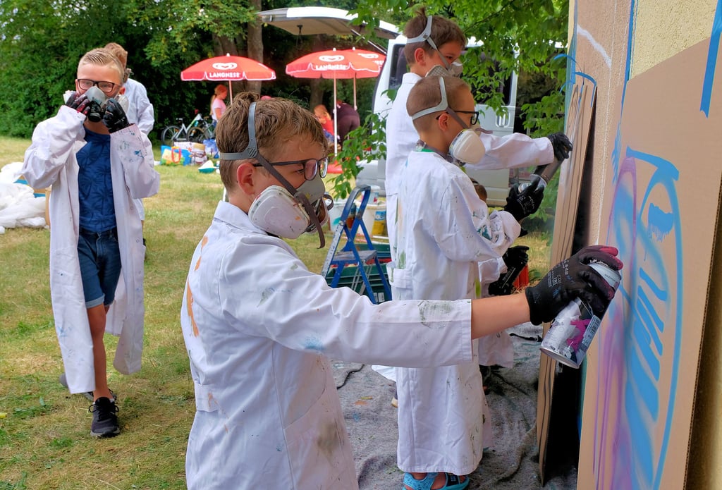 Bevor das Graffiti-Projekt Gestalt annimmt, dürfen die Jugendclub-Kinder ihr Können erst einmal auf einer Pappe ausprobieren.