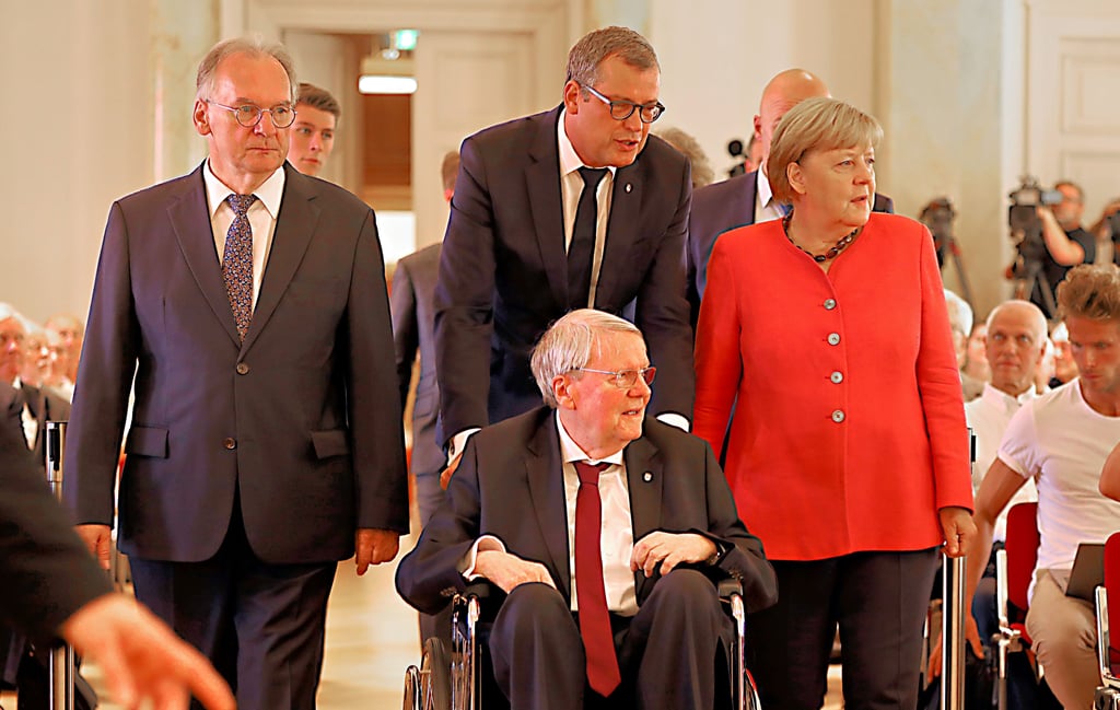 Gemeinsamer Einzug: Leopoldina-Präsident Gerald Haug geleitet Jubilar Jörg Hacker (im Rollstuhl) in den Festsaal, flankiert von Ministerpräsident Reiner Haseloff (links) und Altkanzlerin Angela Merkel.