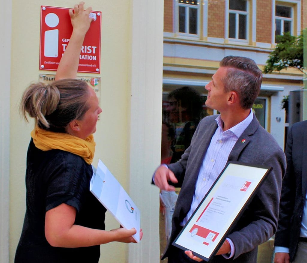Unter Beobachtung von Bürgermeister Benjamin Kanngießer erneuerte Jana Krause das Qualitätssiegel auf dem „i“-Schild.