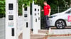 Ein Enercity-Mitarbeiter steht mit einem Elektroauto neben Ladesäulen in einem neuen Ladepark.