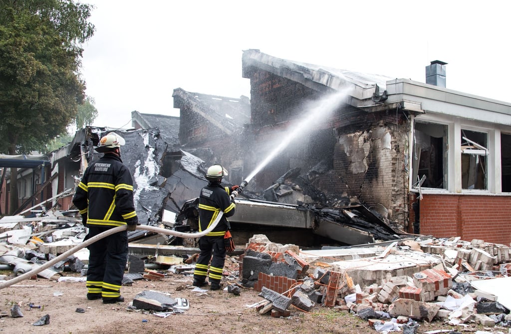 Feuerwehrleute löschen Trümmer eines Gebäudes der Stadtteilschule Finkenwerder.