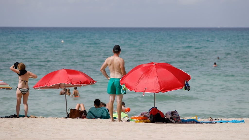 Touristen sonnen sich am Strand von Arenal auf Mallorca - ein Badeverbot könnte das bald verhindern. Foto: Clara Margais/